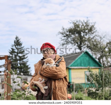 Charming woman in the garden in autumn, wearing a brown jacket and a red beret