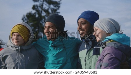 Happy multiethnic friends or family take picture standing on hill against nature scenery. Tourist group of diverse travelers or hiking buddies on trip in mountains. Tourism and active leisure concept.