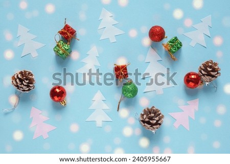 Christmas background.  Christmas balls, pine cones and paper fir-trees on blue background