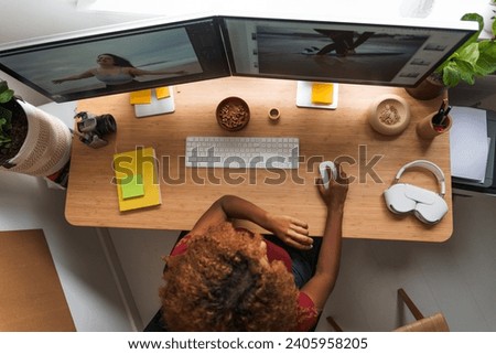 Young creative woman work on phone and computers editing photos at cozy home office