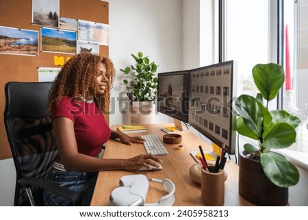 Young creative woman work on phone and computers editing photos at cozy home office
