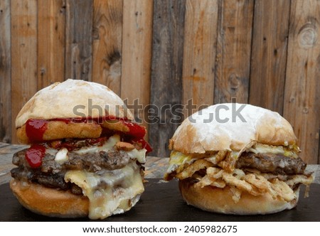 Fast food. Two delicious burgers on a black dish on the restaurant table, with a wooden background. 