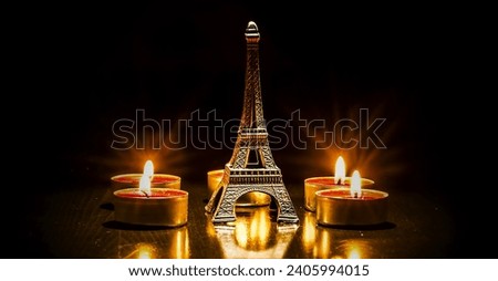 Eiffel tower on the background of colorful lights garland, bokeh. Eiffel tower small model and candle. 