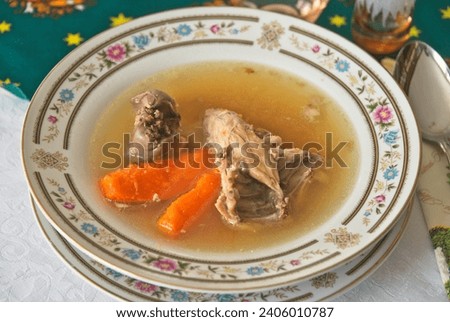 Homemade traditional Hungarian chicken meat broth soup with chicken back, liver and carrot in a porcelain plate. Royalty-Free Stock Photo #2406010787