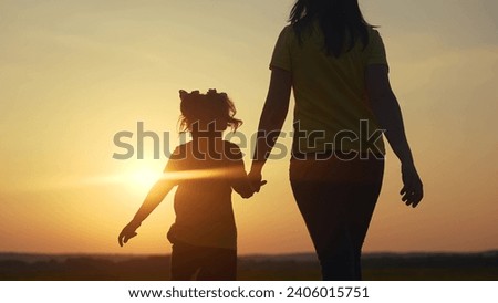 mom and daughter in the park. mom holding her daughter hand walking in the park silhouette at sunset in nature. happy family kid dream concept. mom and kid family walking in nature lifestyle