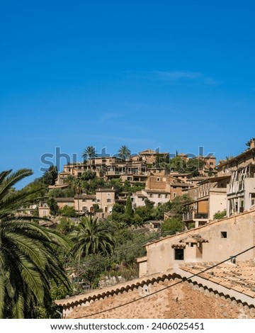 Stunning cityscape of the small coastal village of Deia in Mallorca, Spain. Traditional houses terraced on hills surrounded by green trees. Tourist destinations in Spain. Balearic Islands.  Royalty-Free Stock Photo #2406025451