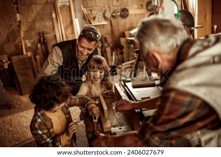 Multigenerational family having fun in woodshop Royalty-Free Stock Photo #2406027679