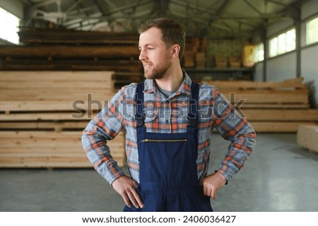 Carpenter in the wood warehouse selects plank for furniture making in the carpentry workshop.