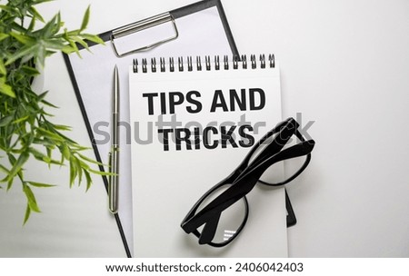 Magnifying glass and notebook with TIPS AND TRICKS word with copy space on wooden table. tips and tricks concept