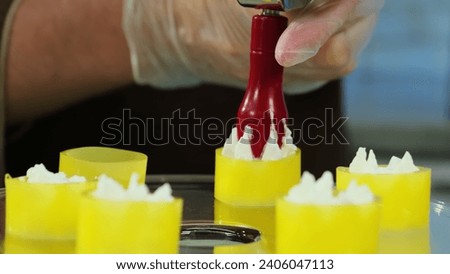 Chef fills jelly tubes with cream using pipping bag. Man creates own dessert vision on transparent plate with cooking devices Royalty-Free Stock Photo #2406047113