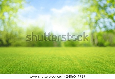 Beautiful blurred background image of spring nature with a neatly trimmed lawn surrounded by trees against a blue sky with clouds on a bright sunny day. Royalty-Free Stock Photo #2406047939