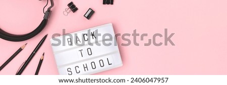 Banner with quote Back to school. Lightbox with letters, headphones and stationery on a pink background. 
