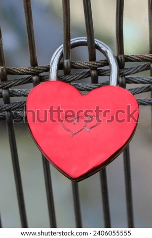 Metal red lock on the bridge with the image of two hearts. The tradition of hanging a lock after the wedding.