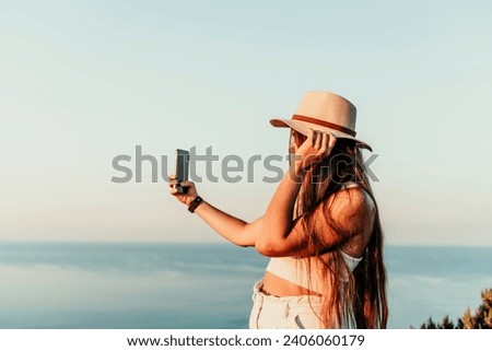 Selfie woman in hat, white tank top and shorts makes selfie shot mobile phone post photo social network outdoors on sea background beach people vacation lifestyle travel concept.