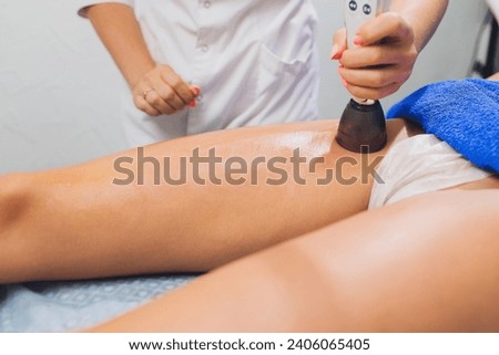 Cropped view of cosmetologist with roller doing buttocks massage