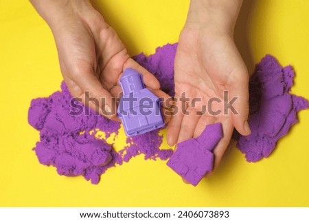 Woman playing with kinetic sand on yellow background, top view Royalty-Free Stock Photo #2406073893