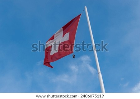 Salez, Switzerland, March 10, 2023 Swiss national flag is waving in the blue sky