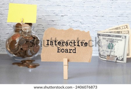 Business concept. Text INTERACTIVE BOARD on notebook with compass and paper clips on wooden table background