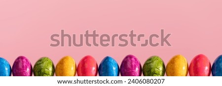Panoramic view of Easter eggs arranged in a single row on a solid pink background. Easter.
