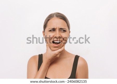 Young woman suffering from jaw pain holding her chin isolated on light background. Inflammation of cervical lymph nodes, Diseases of ENT organs, facial, trigeminal nerve, toothache, dislocation of jaw Royalty-Free Stock Photo #2406082135
