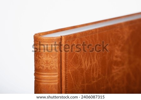 Detail of a Brown leather photo book on white background. Wedding photobook in brown leather binding. Wedding photo book, album family album. Photo book with embossing and a cover of genuine leather.