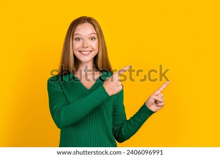 Photo of cute cheerful girl toothy smile direct fingers empty space ad blank isolated on yellow color background