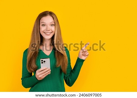 Photo of famous blogger subscribe her new account in social media holding phone direct finger mockup isolated on yellow color background