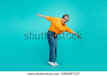 Full size photo of keep balance old woman falling into abyss dangerous tightrope wear orange shirt jeans isolated on blue color background
