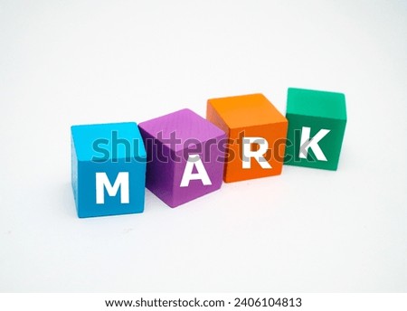 A coloured wooden block with word “MARK” on it