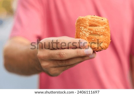 A guy's hand holds a mini puff pastry with cheese, snack and fast food concept. Selective focus on hands with blurred background and copy space for text.