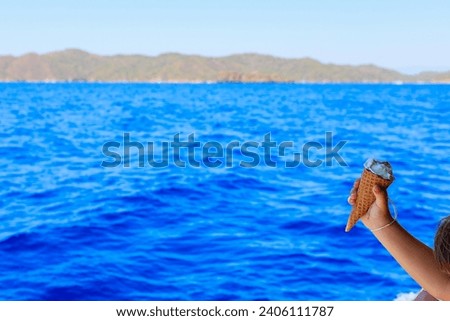 Ice cream in the hands of a child on a yacht on a blurred backdrop of the sea. Background with selective focus and copy space for text