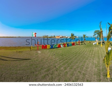Aerial drone tour of a small island with a restaurant and games for children next to huge colorful letters that say "Mexcaltitan"