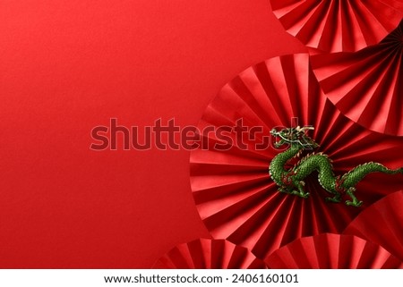 Happy Chinese New Year 2024 flat lay composition. Paper cut folding fans and dragon on red background. Lunar New Year greeting card template.