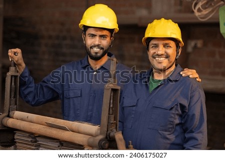 Two male maintenance engineers examining machine at factory