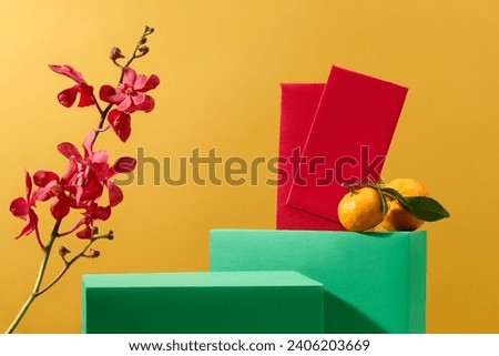 Red envelopes, vibrant orchids and tangerines, the green podium showcases products against a festive yellow backdrop, providing an ideal setting for advertising and display. Royalty-Free Stock Photo #2406203669