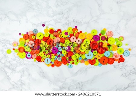 Scattered colorful buttons on white table. Pile of multicolored buttons in a center of the picture. Copy space. Good for logos of sewing or tailoring work. Home needlework. Flat lay banner with button