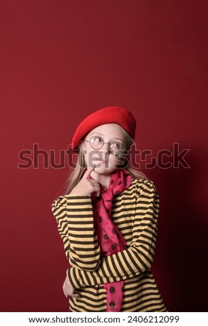 A girl in a red beret, red bow and  yellow striped blouse. Red background. place for text