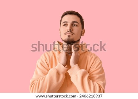 Young man with thyroid gland problem on pink background
