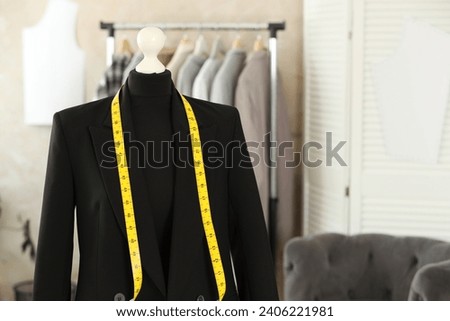 Mannequin with black jacket and measuring tape in tailor shop, space for text Royalty-Free Stock Photo #2406221981