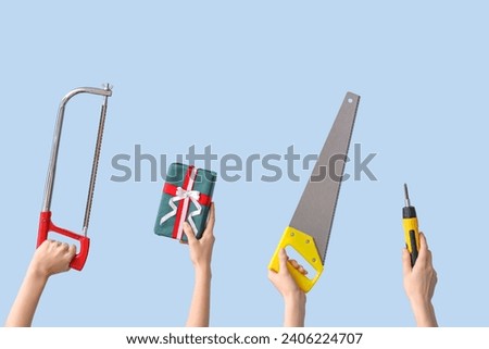 Hands holding construction tools and Christmas decorations on light blue background