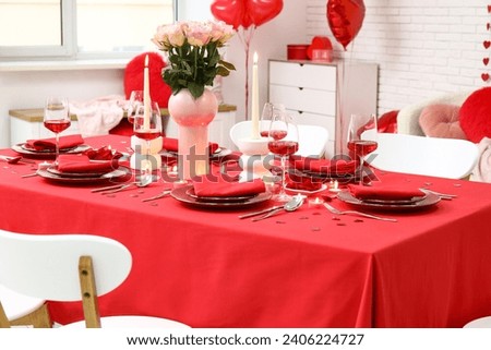 Festive table setting decorated for Valentine's Day with pink roses and candles at home