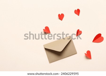 Composition with envelope and red paper hearts on light background. Valentine's Day celebration