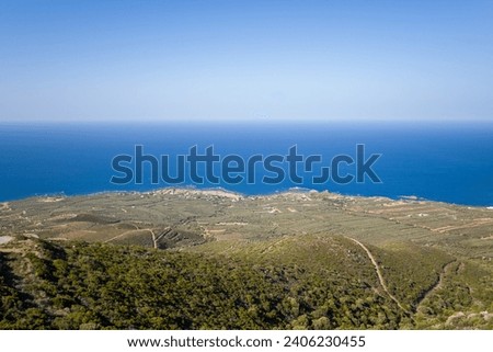The green countryside at the foot of the rocky mountains , in Europe, Greece, Crete, towards Chania, By the Mediterranean Sea, in summer, on a sunny day.