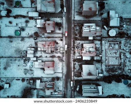 Looking down from an aerial view at houses, streets and backyards in the town during winter.