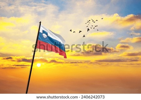 Waving flag of Slovenia against the background of a sunset or sunrise. Slovenia flag for Independence Day. The symbol of the state on wavy fabric.