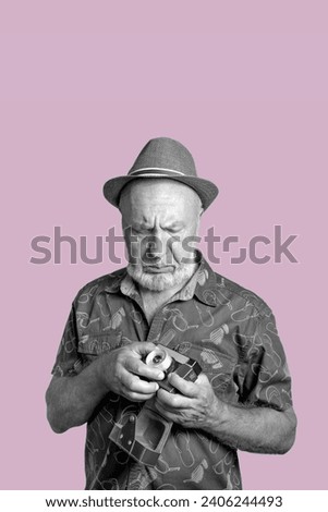 Elderly man with a film camera. The old man tries to remember the settings of the film camera. Retro concept. black and white portrait on pink background