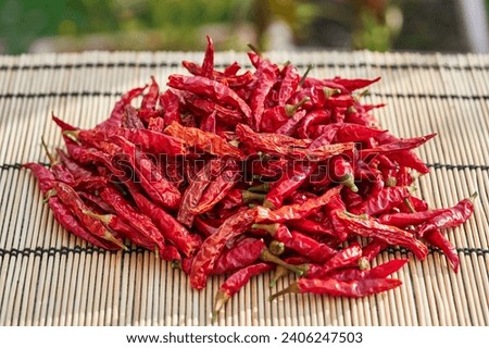 Close up picture on the sun dried red hot chilli peppers on the bamboo mat outside. Traditional dried peppers from organic farming will be used as a condiment in kitchen for cooking of spicy dishes.