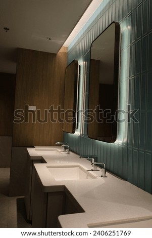 Empty public bathroom with lavatory and wide wall mirror, concept for public toilets.