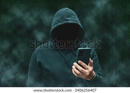 Mysterious faceless hooded anonymous hacker holding smartphone, silhouette of cybercriminal, terrorist. Royalty-Free Stock Photo #2406256407