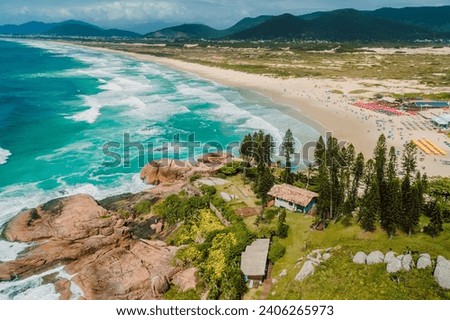 Popular holiday Joaquina beach with trees and ocean with waves in Brazil. Aerial view of coastline Royalty-Free Stock Photo #2406265973